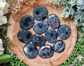 May include: A collection of 10 green and black ocean jasper palm stones. The stones are smooth and polished, with a variety of patterns and swirls.
