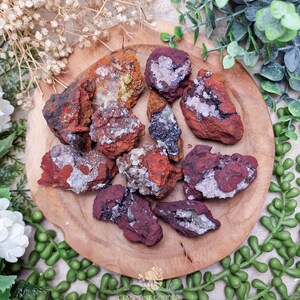 May include: A selection of rough, reddish-brown mineral specimens with white and crystal inclusions, displayed on a round wooden plate. The minerals have a textured surface and vary in size. The image is taken from a top-down perspective.