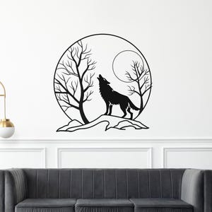 Könnte beinhalten: Schwarze Metall-Wandkunst, die eine Silhouette eines heulenden Wolfs vor Bäumen und einem Vollmond zeigt. Das Kunstwerk ist in einem kreisförmigen Rahmen angeordnet, der einen Kontrast zur weißen Wand bildet. Der Wolf steht auf einem Felsvorsprung.
