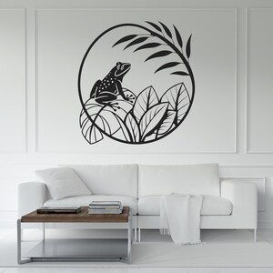 Pode incluir: Arte de parede a preto e branco com um sapo em folhas dentro de uma moldura circular. O design inclui elementos detalhados de folhas e ramos, criando uma estética inspirada na natureza. Adequado para salas de estar, quartos ou qualquer espaço que necessite de um toque de decoração natural.