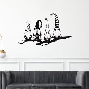 May include: Black silhouette of four gnomes perched on a tree branch. Each gnome has a different hat design, including stripes and a bell. The gnomes have long beards and are facing forward. The artwork is mounted on a white wall.
