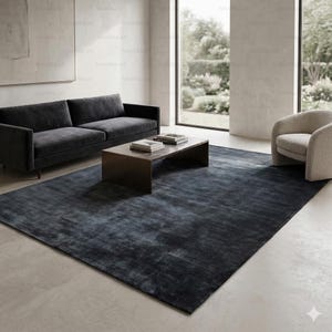 May include: A large, rectangular, dark blue area rug with a subtle, textured pattern. The rug is placed in a modern living room setting, with a dark gray sofa, a wooden coffee table, and a cream-colored armchair.