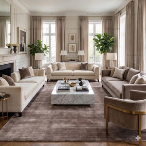 May include: A luxurious living room with neutral tones. Features include three sofas, a marble coffee table, and a large area rug. The room is decorated with plants, lamps, and artwork, creating a sophisticated and inviting atmosphere.