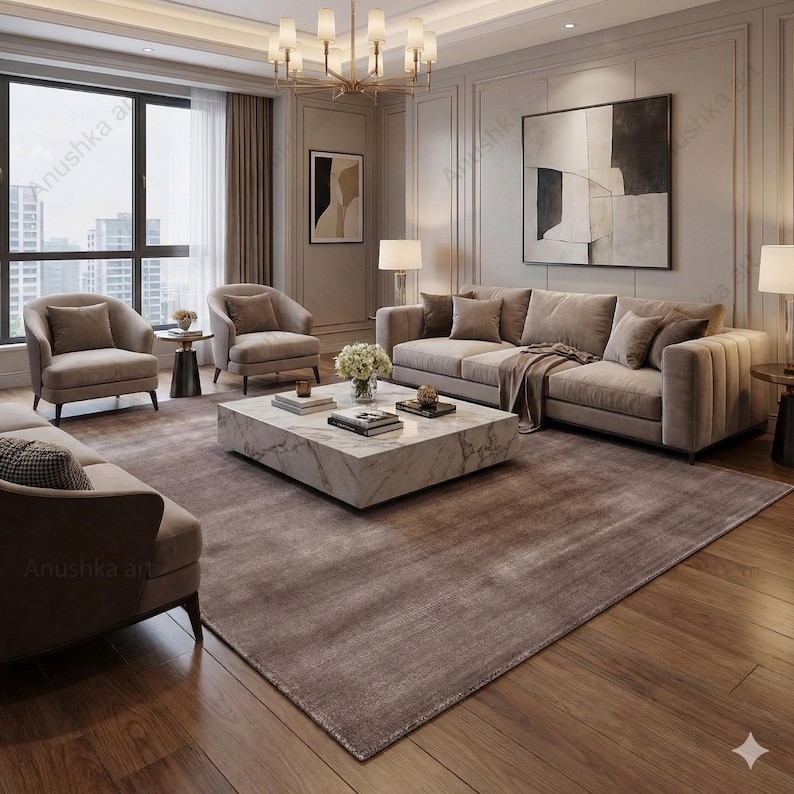 May include: A luxurious living room with a modern design. Features include a large, neutral-toned sofa, two armchairs, and a marble coffee table. A large area rug and hardwood floors complete the space. A chandelier and artwork add to the room's elegance.