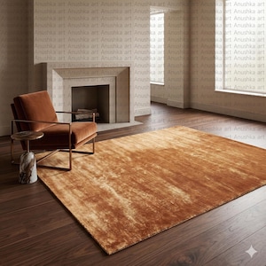 Peut inclure: Un tapis rectangulaire de couleur rouille avec une surface texturée. Le tapis est posé sur un plancher en bois foncé dans une pièce avec une cheminée et un fauteuil moderne. La pièce a une palette de couleurs neutres.