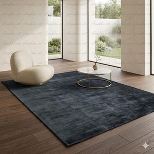 May include: A large, rectangular, dark blue rug dominates a room with a modern aesthetic. A cream-colored armchair and a round marble-topped coffee table with a gold base are also present. The room has large windows and hardwood floors.