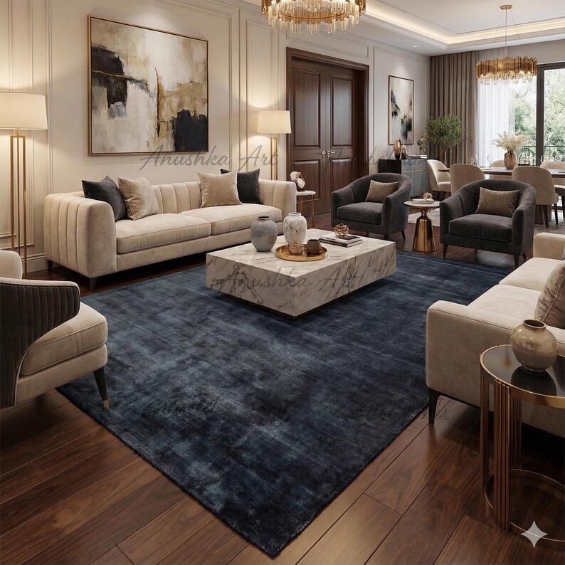 May include: A luxurious living room featuring a large, dark blue area rug, beige sofas, and armchairs. A marble coffee table sits in the center, adorned with decorative vases and trays. The room is illuminated by a chandelier and floor lamps, creating a warm ambiance.