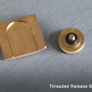 May include: A gold-colored threaded release button for a fidget spinner. The button has a black rubber ring around the top.