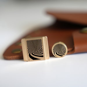 May include: Two brass stamp designs with a black and white swirl pattern. The larger stamp is rectangular and the smaller stamp is round.