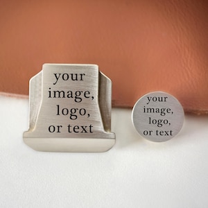 May include: A silver-toned metal stamp with a trapezoidal head and a circular metal stamp, both featuring a brushed finish and the engraved black text "your image, logo, or text" on their flat surfaces for custom branding and marking purposes.