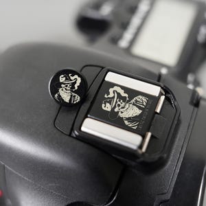 Könnte beinhalten: Eine weiße Keramik-Tasse mit schwarzem Henkel und dem Text "But First, Coffee" in handschriftlichem Stil. Die Tasse steht auf einer weißen Oberfläche. Die Tasse ist etwa 10 cm hoch.