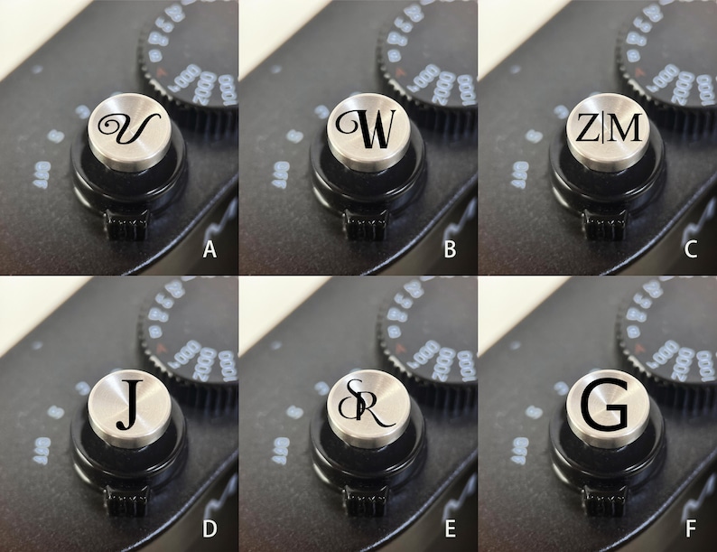 Op de afbeelding: Close-up van een zwarte camerabody met een zilveren draaiknop met de letter "V". De draaiknop is omgeven door een zwarte bedieningsring met witte markeringen. De achtergrond toont andere draaiknoppen met cijfers.