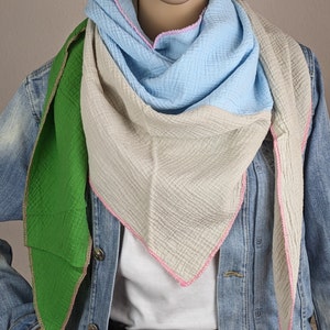 May include: A triangular scarf with a light blue, beige, and green color scheme. The scarf has a pink stitched border.