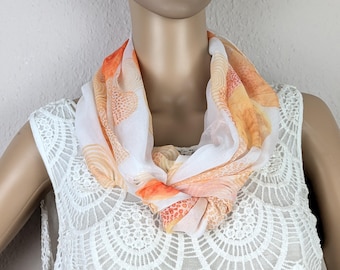 May include: A white sheer scarf with orange and yellow abstract patterns. The scarf is tied around the neck of a mannequin.
