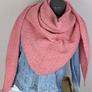 Könnte beinhalten: Ein staubrosa Dreieckstuch, drapiert über einer Jeansjacke. Der Schal hat ein strukturiertes Aussehen und ist um den Hals einer Schaufensterpuppe gewickelt. Die Jeansjacke ist hellblau und darunter befindet sich ein weißes Hemd.