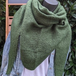 Può includere: Una sciarpa verde scuro e soffice con una forma triangolare. La sciarpa è drappeggiata intorno al collo e alle spalle di un manichino.