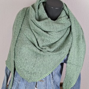 Könnte beinhalten: Ein weicher, grüner Strick Schal mit einem hellgrünen Stich Detail an den Rändern. Der Schal ist über eine Jeansjacke gelegt.