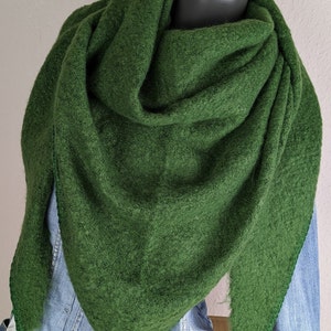 Könnte beinhalten: Ein dunkelgrüner, dreieckiger Schal aus einem strukturierten Stoff. Der Schal ist auf einer Jeansjacke an einer Schaufensterpuppe drapiert. Die Farbe des Schals ist ein tiefes, sattes Grün, und der Stoff wirkt weich und warm.