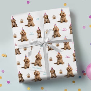 May include: White wrapping paper with a repeating pattern of brown dogs wearing party hats and holding cupcakes. The text "Happy Birthday!" is printed on the paper.