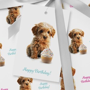 May include: White gift tags featuring a light brown puppy and a cupcake with colorful sprinkles. The tags have the text "Happy Birthday!" in teal. A grey ribbon is visible in the background.