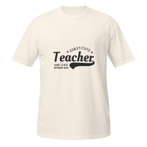 Puede incluir: Camiseta color crema con las palabras "Substitute Teacher" en una fuente negra estilizada. El texto "Same Class, Different Boss" está debajo. Puntos rojos acentúan la palabra "Substitute".