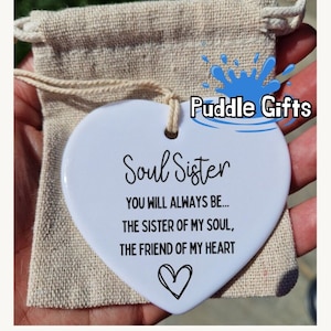 Pode incluir: Ornamento de cerâmica branco em forma de coração com o texto "Soul Sister You Will Always Be... The Sister Of My Soul, The Friend Of My Heart" e um pequeno desenho de coração.
