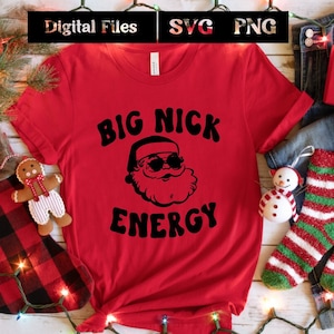 May include: Red t-shirt with a black graphic of Santa Claus wearing sunglasses and the text "BIG NICK ENERGY".
