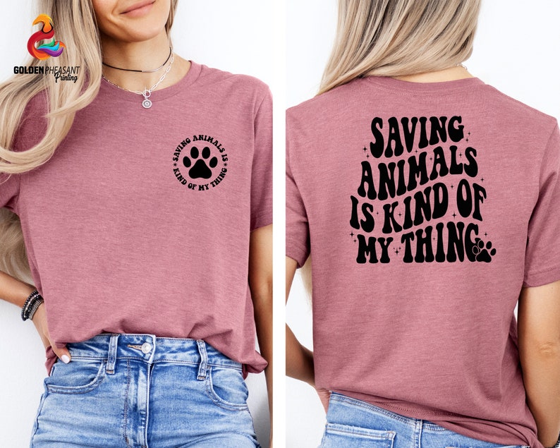 May include: A pink t-shirt with the text "Saving Animals is Kind of My Thing" on the back and a paw print with the text "Saving Animals is Kind of My Thing" on the front.