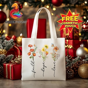 May include: A white tote bag with floral watercolor designs and the words "faith, hope, love" in a script font. The bag has two white handles and is surrounded by Christmas decorations.