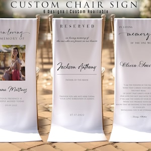May include: White custom chair signs with elegant calligraphy. The signs read "in loving memory of" with names and dates, and "reserved" for a wedding. The signs are displayed on chairs, perfect for memorial or wedding events.