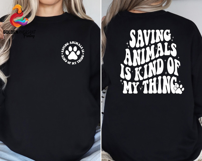 May include: Black sweatshirt with white text that reads "Saving Animals is Kind of My Thing" with a paw print.