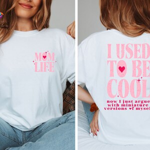 May include: White t-shirt with pink text that says "MOM LIFE" with a pink heart on the front and a white t-shirt with pink text that says "I USED TO BE COOL now I just argue with miniature versions of myself" on the back.