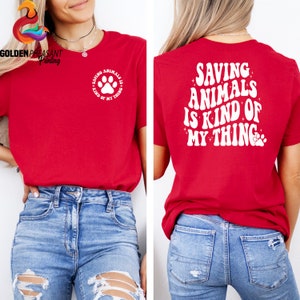 May include: Red t-shirt with the text "Saving Animals is Kind of My Thing" in white with a paw print. The back of the shirt has the same text in a larger font with a paw print.