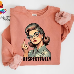 May include: A coral-colored sweatshirt featuring a retro-style illustration of a woman wearing glasses and giving the middle finger. The word "RESPECTFULLY" is printed in red below the image. The Golden Pheasant Printing logo is in the upper left corner.
