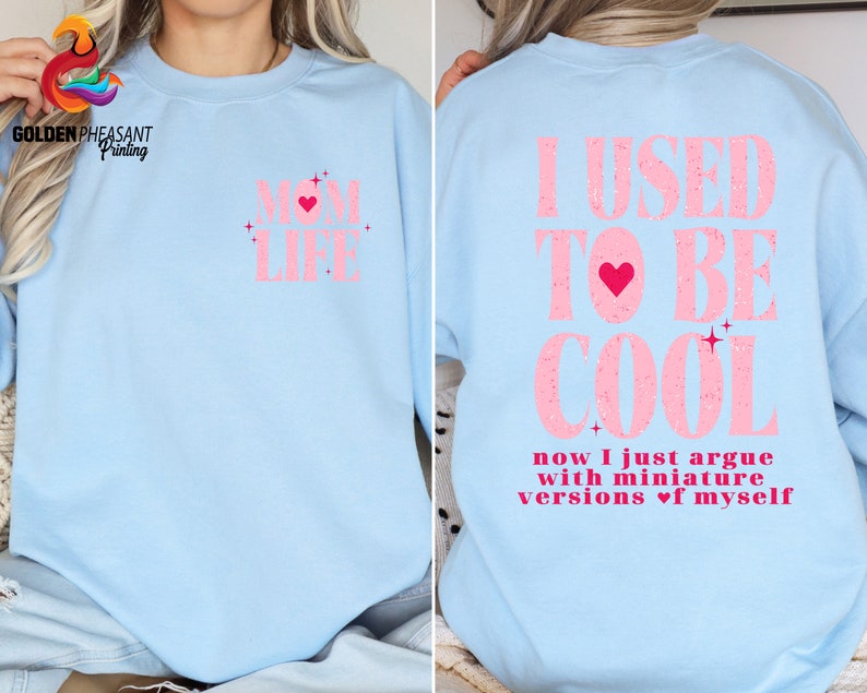 May include: Light blue sweatshirt with pink text that reads "I USED TO BE COOL now I just argue with miniature versions of myself" with a pink heart in the text.