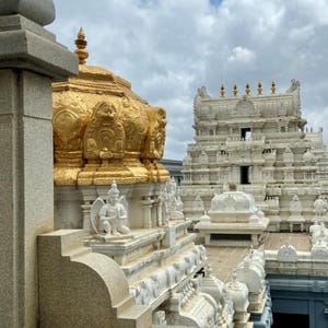 May include: An architectural image of a temple with gold and white structures. The gold dome is ornate, and the white structures have intricate carvings. The sky is cloudy with patches of blue.