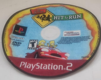 Op de afbeelding: Rond tapijt met het videospel "Hit & Run". Het tapijt heeft een rode rand en een blauw en geel midden met het logo van het spel, personages en het PlayStation 2-logo. Het tapijt is een decoratief item.