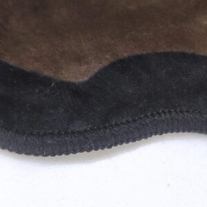 May include: A brown rug with a black, wavy, fringed border.