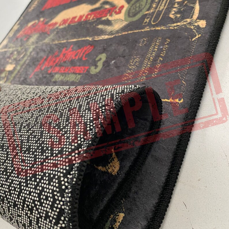 May include: A black and red rug with a graphic print of the movie "A Nightmare on Elm Street 3: Dream Warriors". The rug has a black border with white stitching.