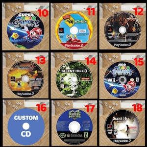 Pode incluir: Uma cole&ccedil;&atilde;o de discos de videojogos com gr&aacute;ficos coloridos. Os discos apresentam t&iacute;tulos como "Super Mario Galaxy", "Hit & Run", "Shadow Hedgehog" e "Silent Hill 3". Os discos est&atilde;o numerados.