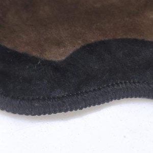 May include: A brown rug with a black, wavy border. The rug has a soft, fuzzy texture.