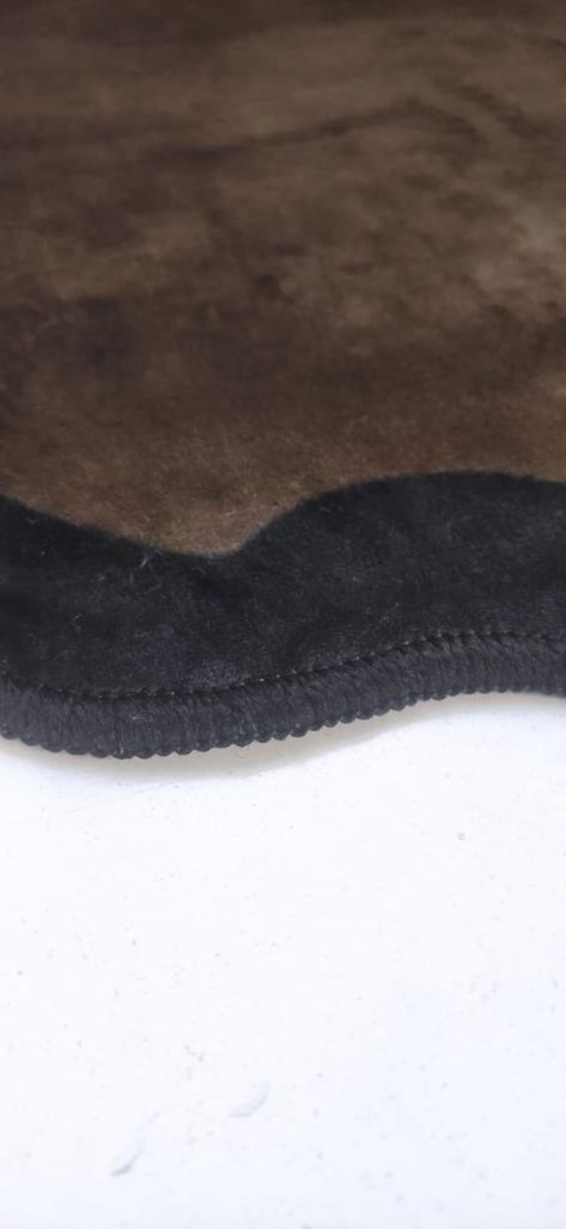 May include: A brown rug with a black, wavy border. The rug has a soft, fuzzy texture.