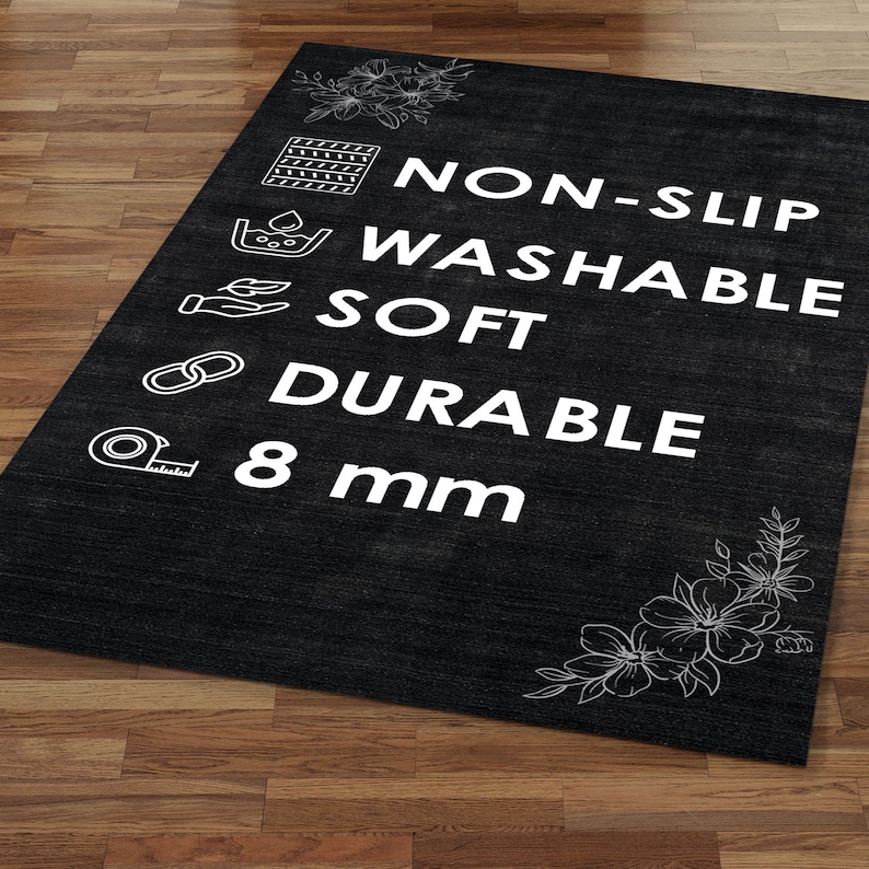 Pode incluir: Um tapete retangular preto com texto branco e desenhos florais nos cantos. O texto diz "NON-SLIP, LAV&Aacute;VEL, MACIO, DUR&Aacute;VEL, 8 mm". O tapete est&aacute; colocado sobre um ch&atilde;o de madeira.