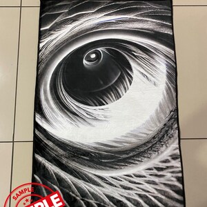 May include: Black and white abstract rug with a large eye-like design. The rug has a soft, plush texture.
