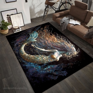 Puede incluir: Una alfombra negra con una ilustración de sirena. La sirena tiene el pelo largo y suelto, una cola azul y un sujetador de concha dorada. El fondo es azul oscuro con purpurina dorada.