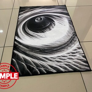 May include: Black and white abstract rug with a large eye design. The eye is surrounded by swirling lines and patterns.