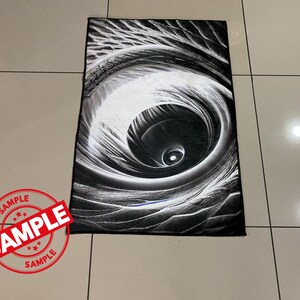 May include: Black and white abstract rug with a swirling design that resembles an eye. The rug has a soft, plush texture.