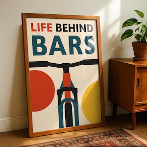 Puede incluir: Una impresión artística enmarcada con un tema de bicicleta. La impresión presenta las palabras "LIFE BEHIND BARS" en rojo y verde azulado, con una ilustración estilizada de una bicicleta. Círculos rojos y amarillos están a cada lado de la bicicleta. El marco es de madera.