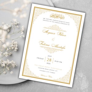 May include: A white wedding invitation with gold calligraphy and ornate borders. The invitation announces the marriage of Aryaan Khan and Fatima Mustafa on Friday, July 28, 2025 at 8:00 PM at The Great Hotel Auditorium, Country Road Avenue 477, Istanbul City, Turkey.