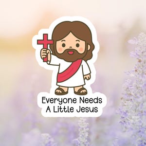 May include: A sticker featuring a cartoon illustration of Jesus holding a red cross. He has brown hair and a beard, wearing a white robe with a red sash. The text "Everyone Needs A Little Jesus" is below the image.